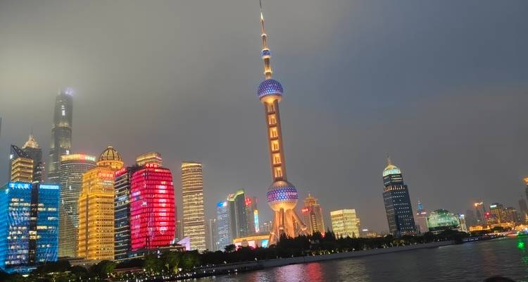 Skyline nocturno de Shanghái con la Torre Perla Oriental brillantemente iluminada reflejada en el río