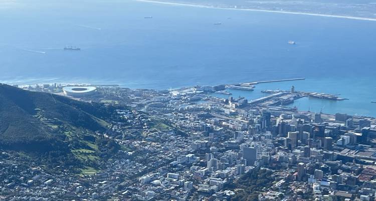 Vista aérea de Ciudad del Cabo con la Cabeza de León, el estadio y la ciudad extendiéndose a lo largo de la costa bajo cielos azules brillantes