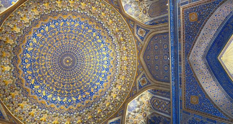 Ingewikkeld gemusterd blauw-en-gouden Islamitische koepelplafond in een historische madrasah.
