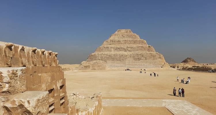 La Pyramide à degrés de Djéser dominant le plateau de Saqqarah avec des touristes en exploration.