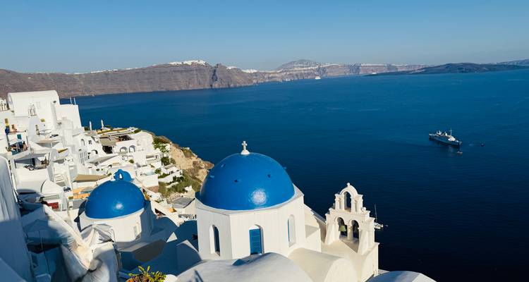Iconic white churches with blue domes overlooking the deep blue Aegean Sea in Oia