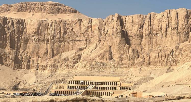 The terraced Temple of Hatshepsut nestled against towering cliffs in the Egyptian desert under clear skies.