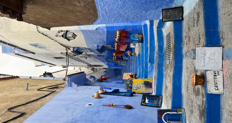 Narrow blue-painted stairway in Chefchaouen lined with local artwork and colorful crafts