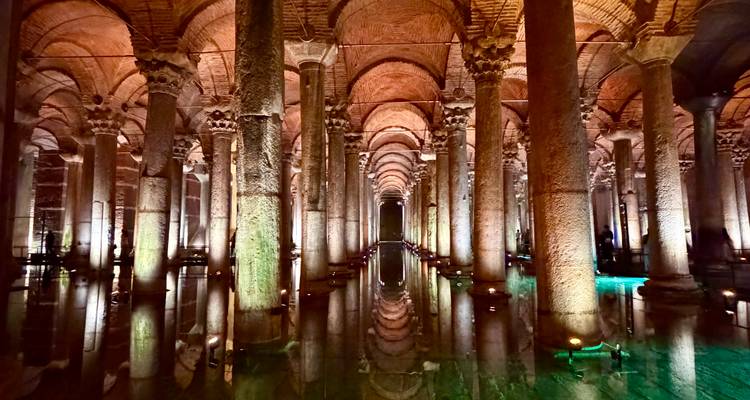 Melancholische, symmetrische blik over de verlichte zuilen en spiegelende wateren van Istanbuls Basilica Cistern.