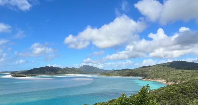 Vue panoramique des criques turquoise, des sables blancs et des îles forestières sous des nuages épars