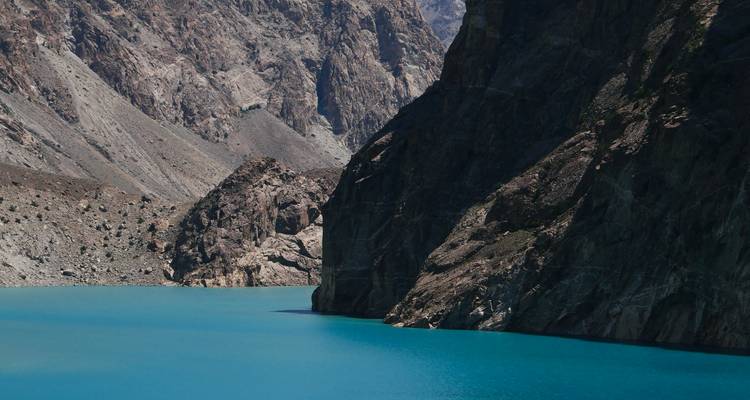 Lago de montaña turquesa rodeado de acantilados rocosos escarpados en Pakistán de gran altitud.