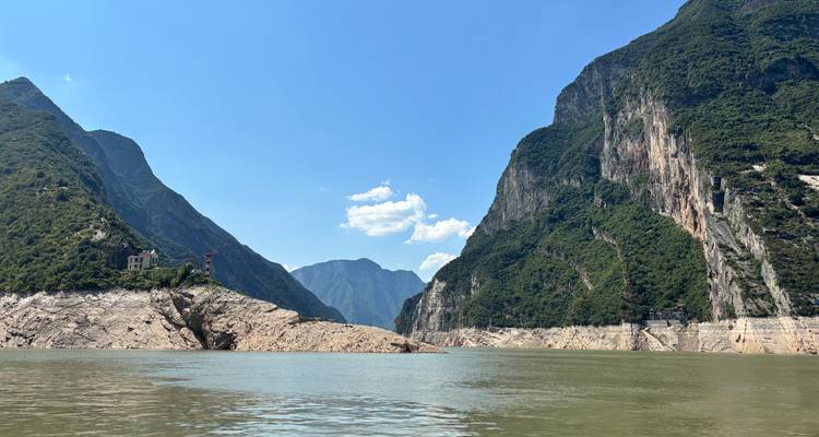 Los acantilados verdes y escarpados se despeñan en el ancho río Yangtsé bajo un cielo azul despejado.