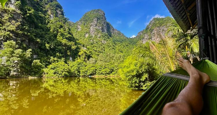 Vue relaxante depuis un hamac surplombant un lac vert et calme, entouré de falaises abruptes couvertes de jungle
