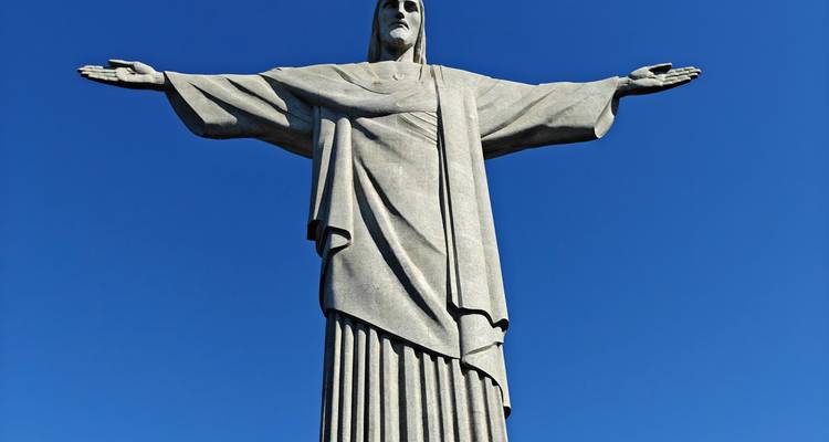 Vue ascendante de la statue emblématique du Christ Rédempteur sur un ciel bleu impeccable.
