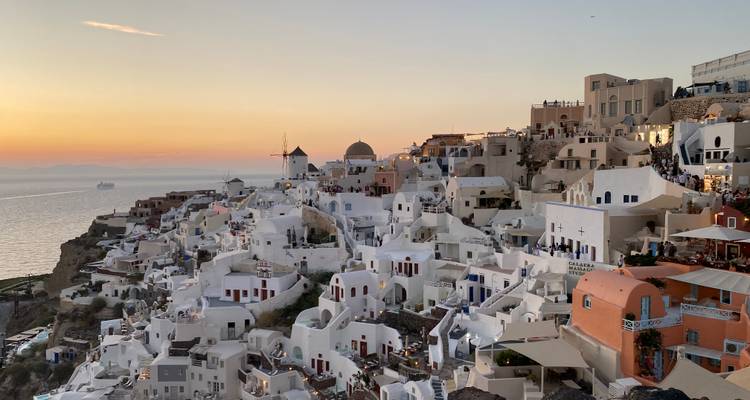 Icónico pueblo acantilado de Oia con casas blancas cúbicas que brillan al atardecer sobre el Mar Egeo