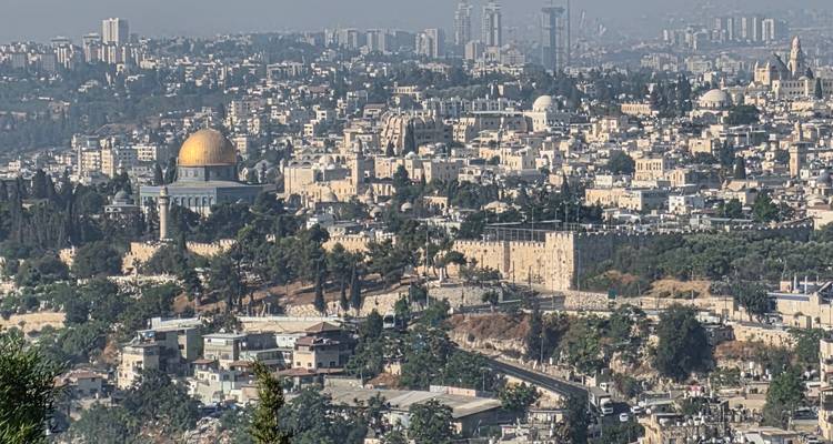 Paisaje urbano panorámico de Jerusalén que presenta el Monte del Templo de cúpula dorada en medio de densos edificios históricos.