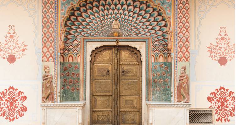 Portail du Paon Vibrant au Palais de la Ville de Jaipur avec des motifs ornés bleu-vert et or encadrant une porte en bronze.