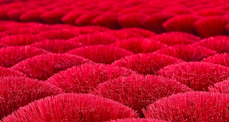 Filas de cerca de palitos de incienso rojo brillante empaqueados para secar crean un patrón vibrante.