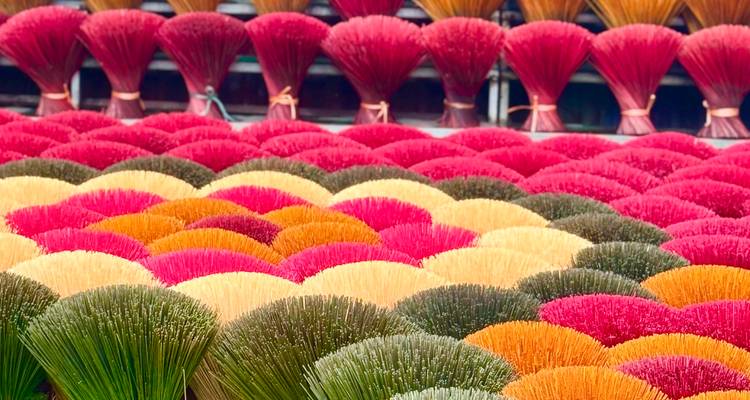 Abanicos multicolores de palitos de incienso exhibidos en filas, formando un arcoíris de tonos.