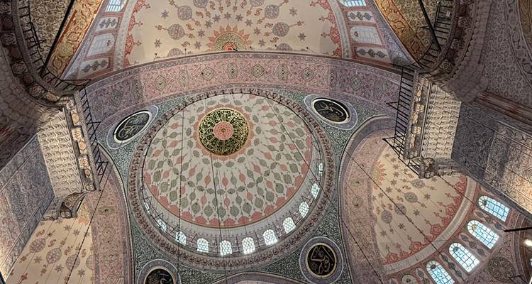 Plafond dôme orné d'une mosquée ottomane présentant des motifs de carreaux floraux et géométriques complexes ainsi que de la calligraphie.