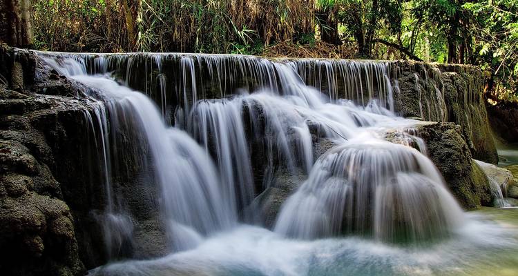 Silky turquoise cascades of Kuang Si Waterfall spilling over limestone tiers amid lush forest.
