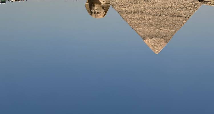 Iconische Grote Piramide van Giza en de Sphinx onder een helder blauwe woestijnhemel.