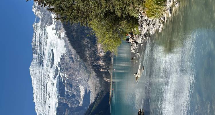 Lac glaciaire emblématique aux eaux émeraude reflétant les sommets enneigés et un glacier suspendu massif