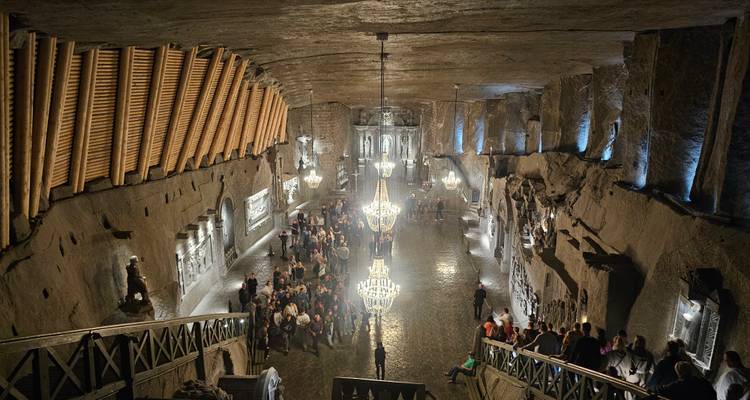 Beleuchteter Kronleuchtersaal aus Salz, tief in das Salzbergwerk Wieliczka hineingehauen, voller Besucher.