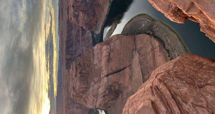 Le fleuve Colorado serpente autour de Horseshoe Bend au coucher du soleil, vue depuis le bord abrupt d'une falaise.