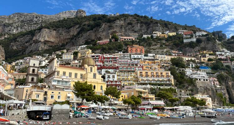 Flanc de colline emblématique de Positano avec des bâtiments colorés empilés s'élevant contre des falaises escarpées et le ciel bleu.