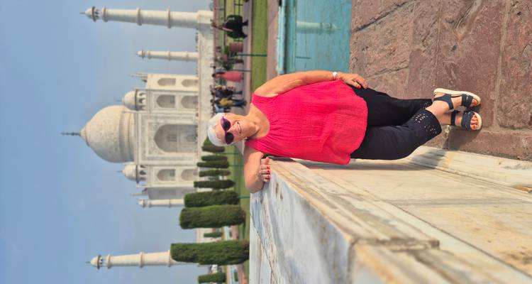 Viajero posando frente al icónico Taj Mahal de mármol blanco en un día despejado.