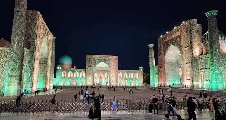 La Plaza Registan iluminada con sus magníficas madrasas brillando en verde contra el cielo nocturno.