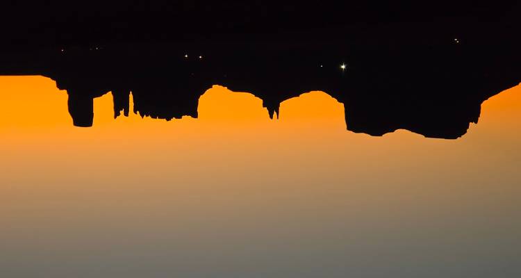 Les mesas en silhouette de la Monument Valley se dressent contre un horizon d'aube d'un orange éclatant.