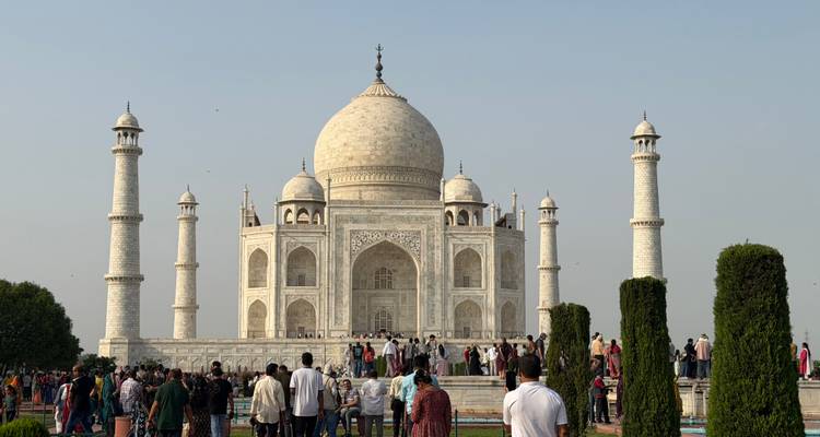 El icónico Taj Mahal de mármol blanco se alza majestuosamente con multitudes reunidas en los jardines del frente.