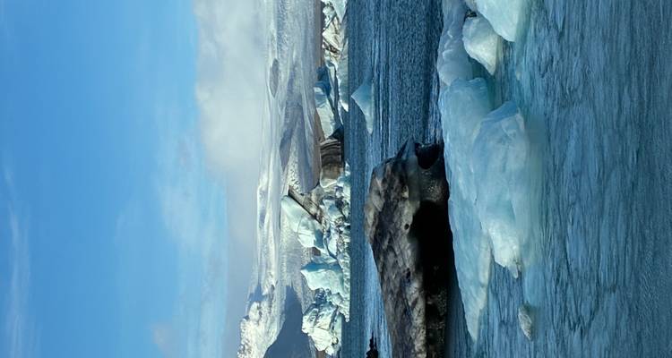 Lagon bleu éclatant rempli d'icebergs flottants sous un ciel dégagé.