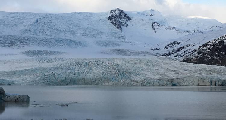 Gletscherblick mit verschneiten Bergen im Hintergrund.