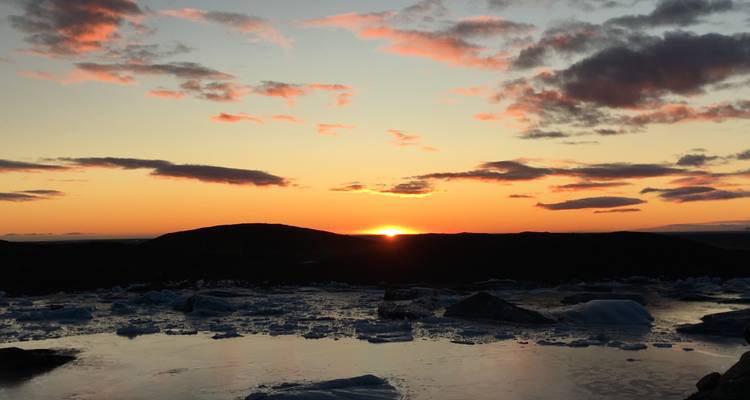Spektakulärer Sonnenuntergang über einer gefrorenen Landschaft mit Eisbergen.
