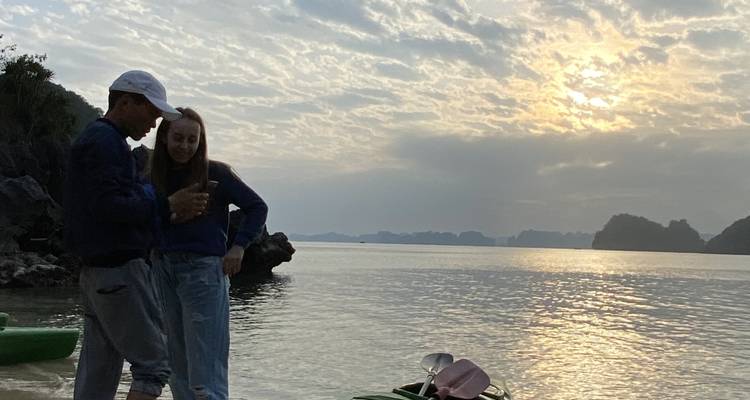 Two people with a kayak on a beach at sunset.