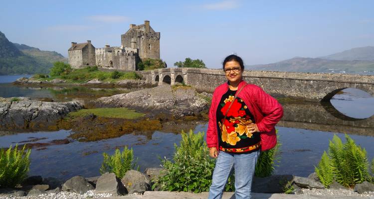 Vrouw staat bij Eilean Donan Castle met een stenen brug.