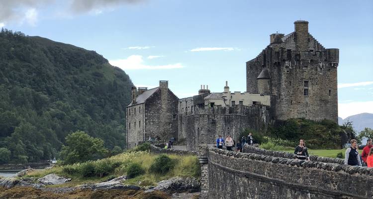 Castillo histórico con personas caminando por un sendero de piedra cercano.