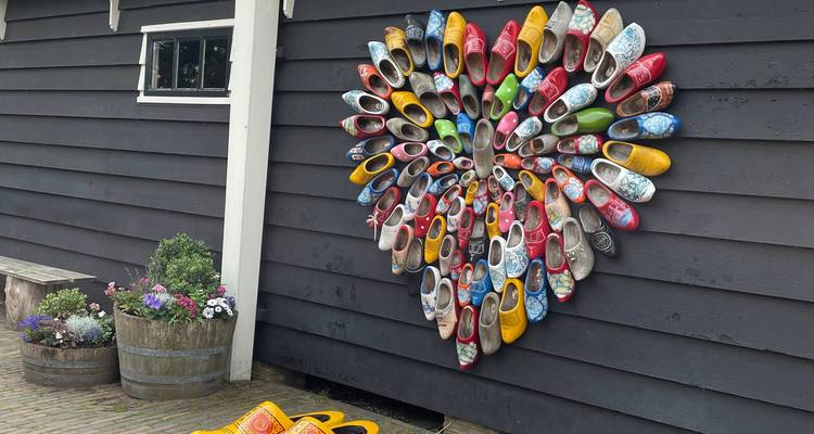 Wall with a variety of colorful wooden clogs displayed.