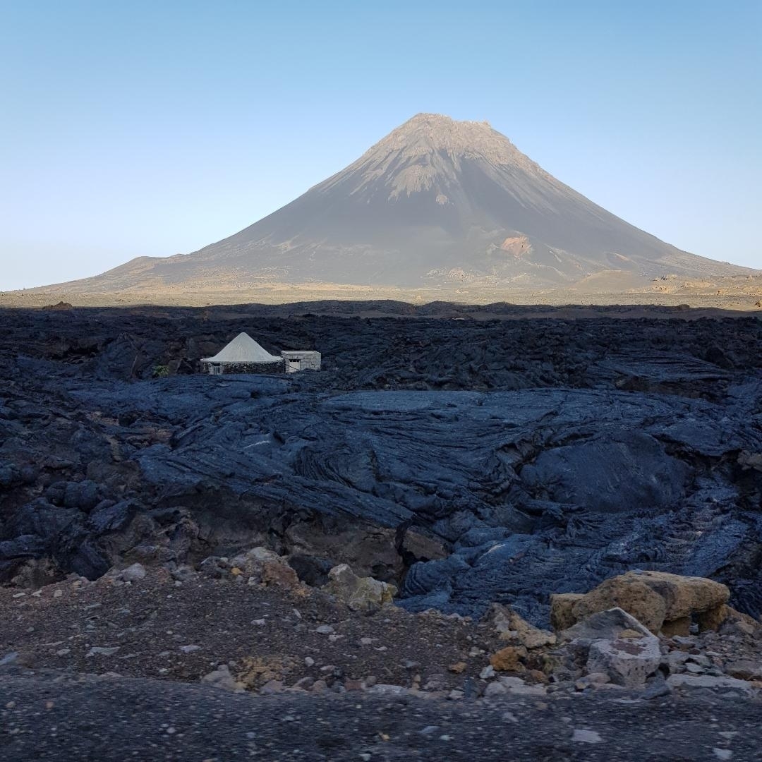 Volcanic landscape with a prominent peak in the background.