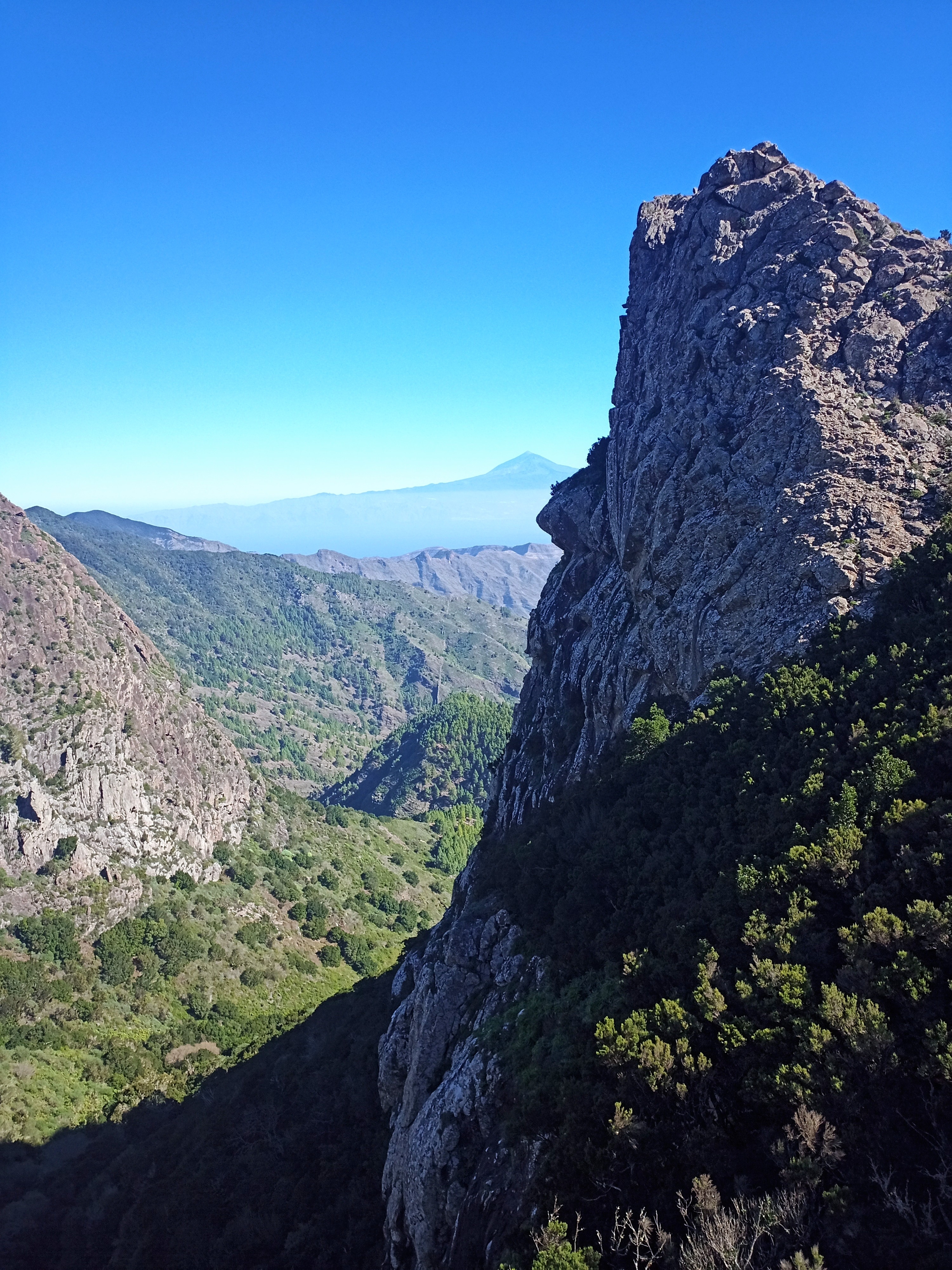 Mountain range with a distant peak under a clear blue sky.