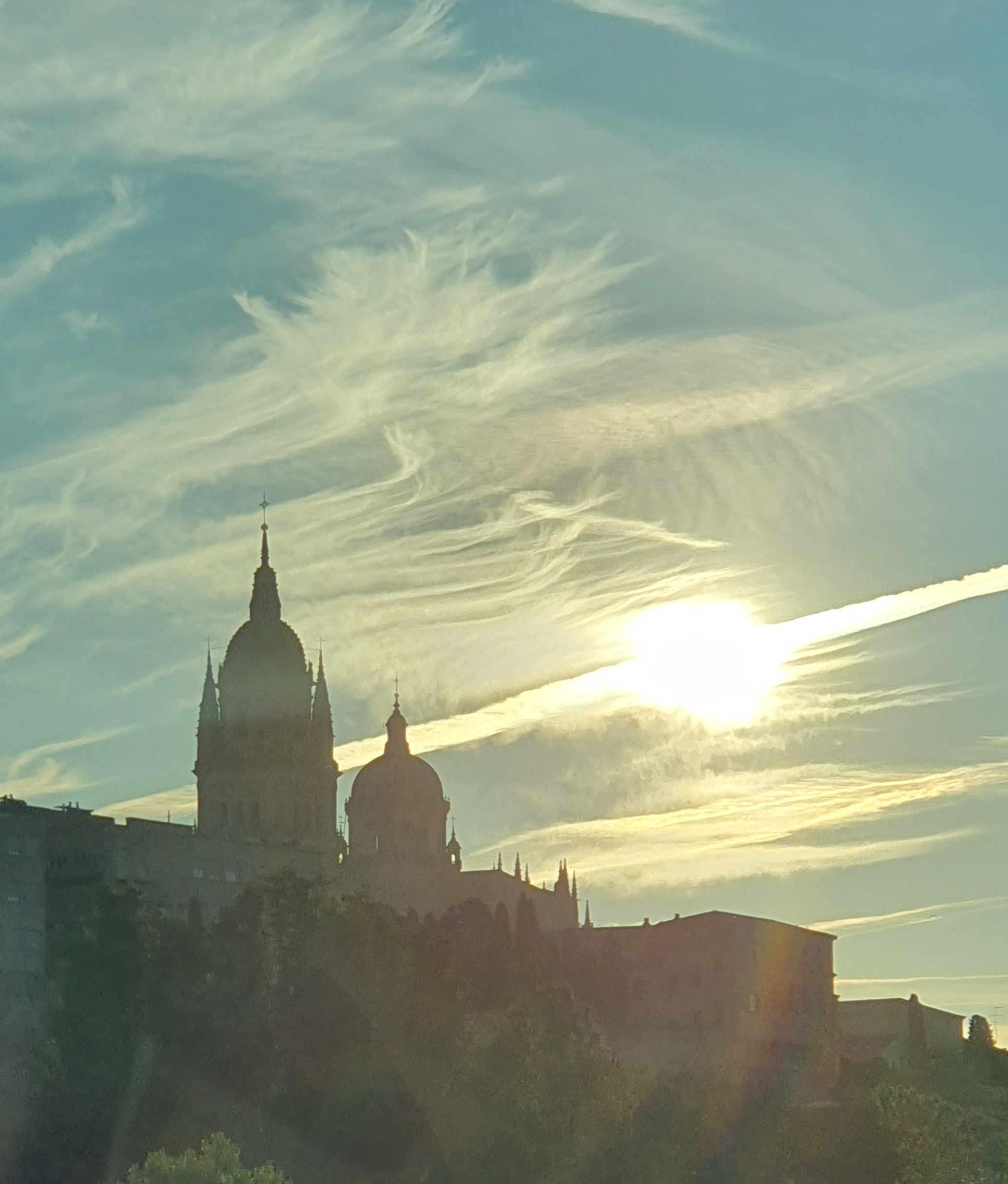Silhouetted domes and spires of a cathedral at sunset with dramatic clouds.