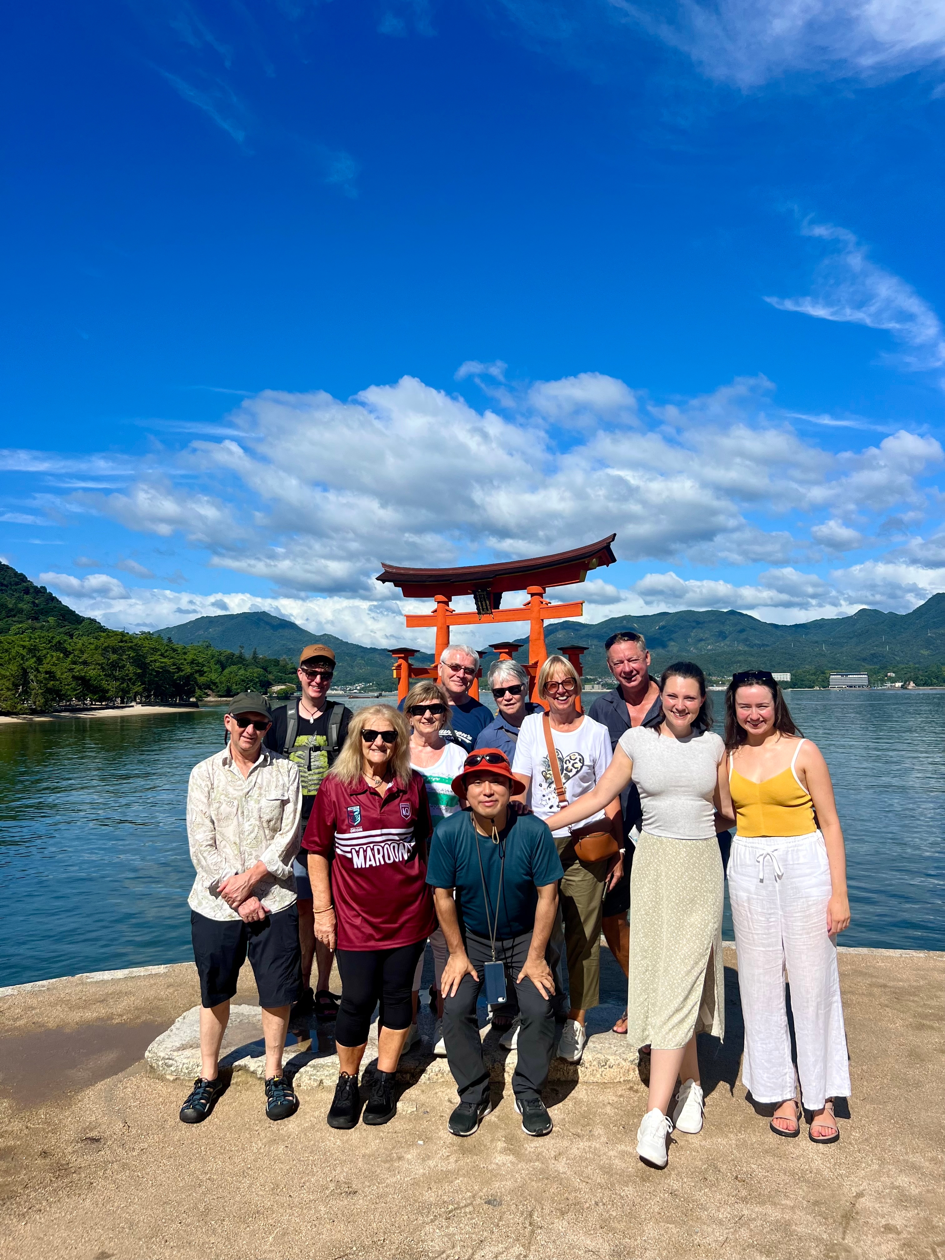 Group posing in front of the iconic Torii gate at the water's edge.