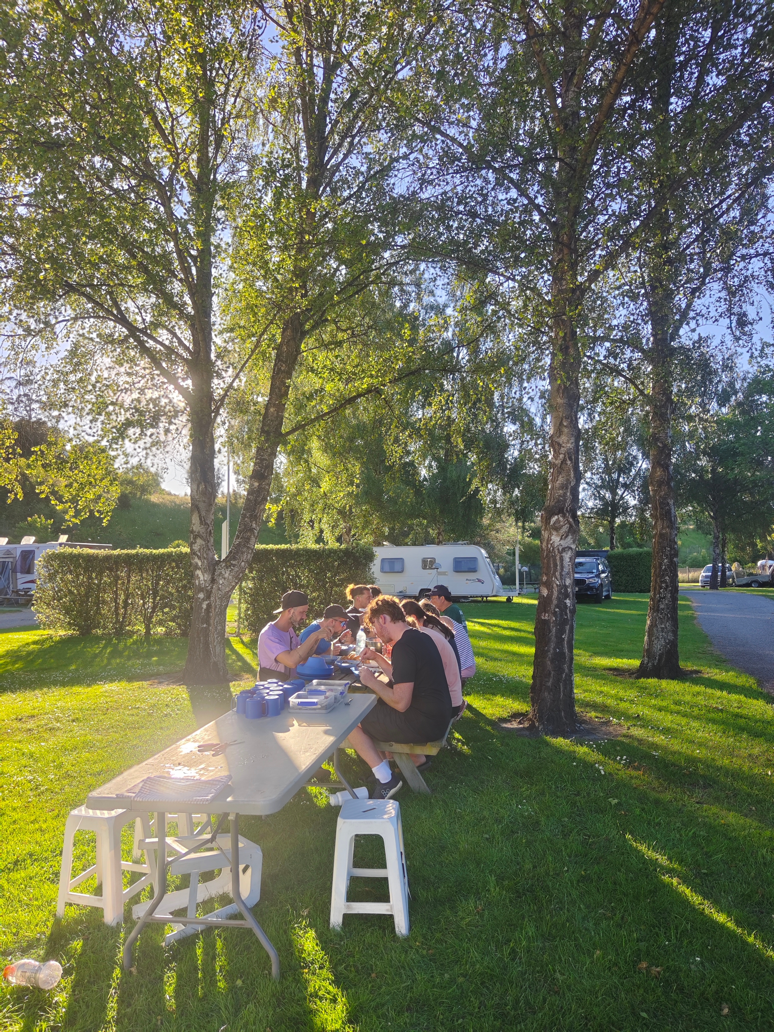 Outdoor picnic with people sitting at a table with caravans nearby