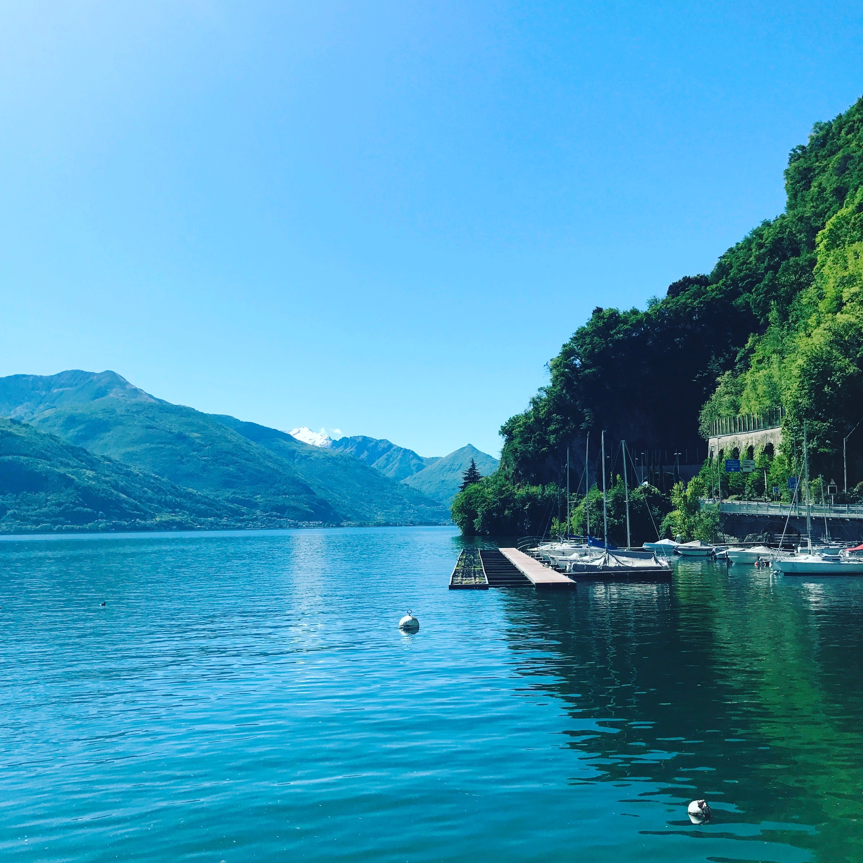 Beautiful lake with yachts and mountains in the background.