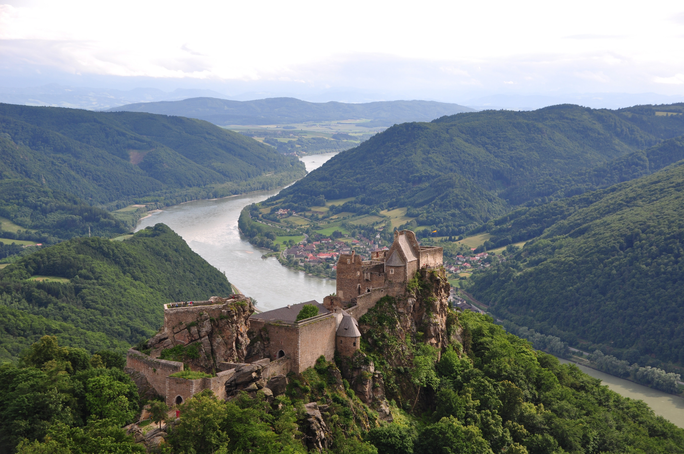 a castle on a hill overlooking a river and lush countryside.