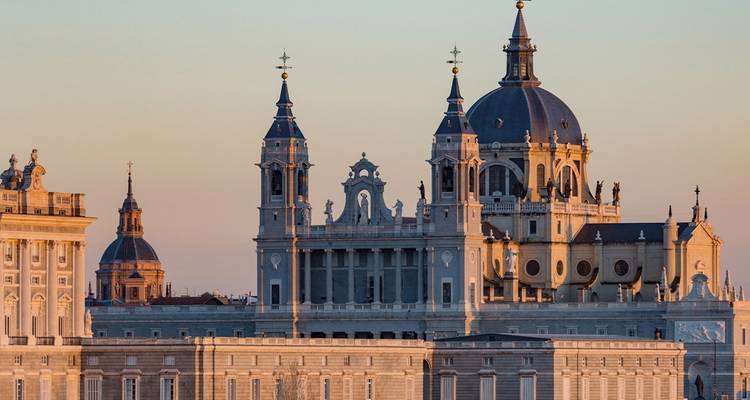Almudena Cathedral’s elegant blue domes and spires glowing in the warm light of sunset over Madrid.