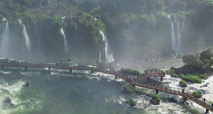 Weids uitzicht op de Iguazu-watervallen met nevel en een golvende loopbrug vol bezoekers