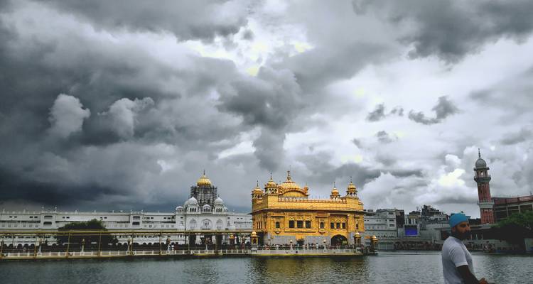 El Templo Dorado brilla bajo dramáticas nubes de tormenta reflejadas en el lago.