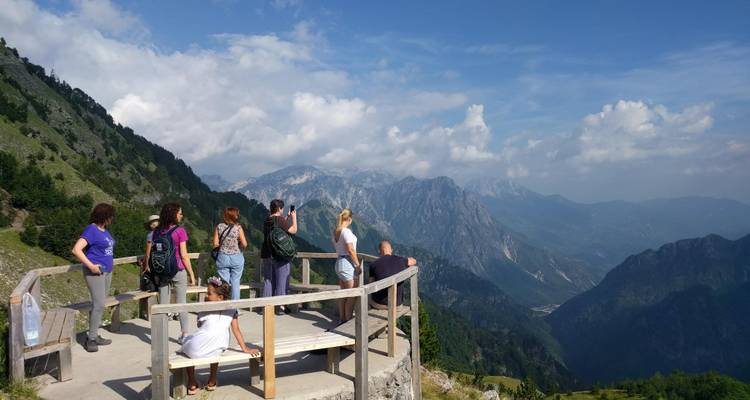 Touristen genießen einen Bergblick von einer hölzernen Aussichtsplattform.