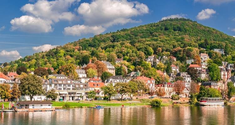 A vibrant town with colorful houses on a hillside by a river.