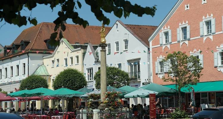 Une rue charmante avec des tables de café et des parasols colorés.
