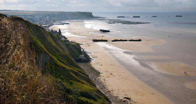 Vue large d'une plage vide avec des vestiges de bunkers.